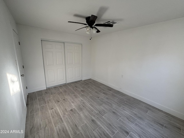 unfurnished bedroom featuring ceiling fan, light wood-type flooring, and a closet