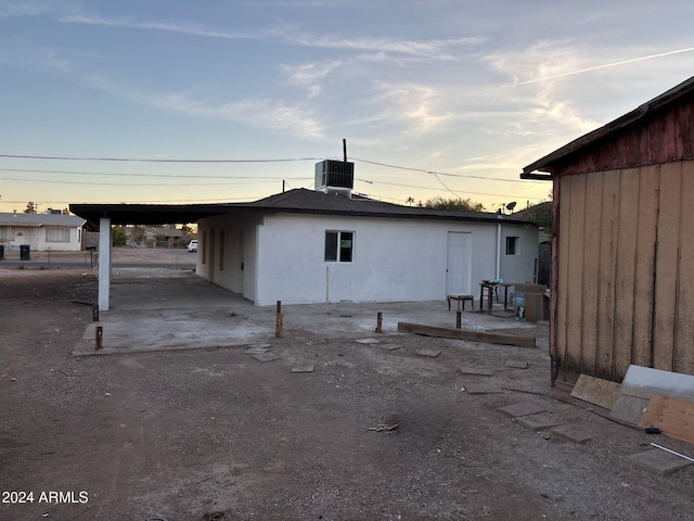 back house at dusk with central AC and a carport