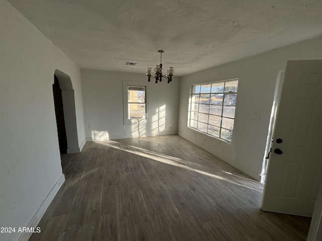 unfurnished dining area with dark hardwood / wood-style floors and an inviting chandelier