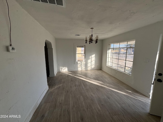 unfurnished dining area featuring dark wood-type flooring and a chandelier