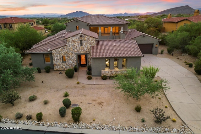 mediterranean / spanish-style home with stone siding, a tile roof, a mountain view, and an attached garage