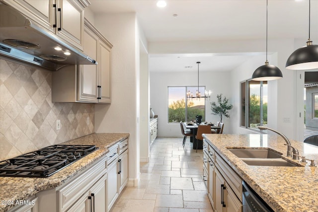 kitchen featuring stone tile floors, baseboards, under cabinet range hood, black appliances, and a sink