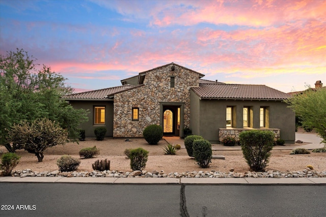 mediterranean / spanish-style house featuring stone siding, a tiled roof, and stucco siding