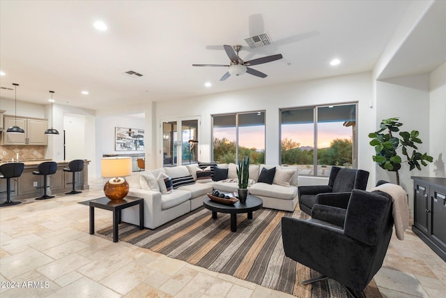 living area with a ceiling fan, visible vents, stone tile flooring, and recessed lighting