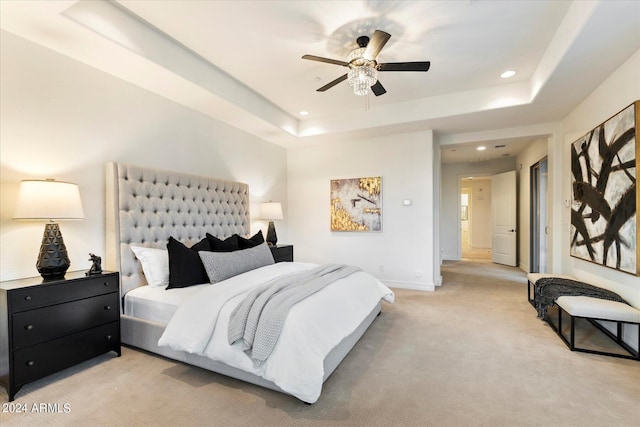 bedroom with a tray ceiling, light carpet, baseboards, and recessed lighting