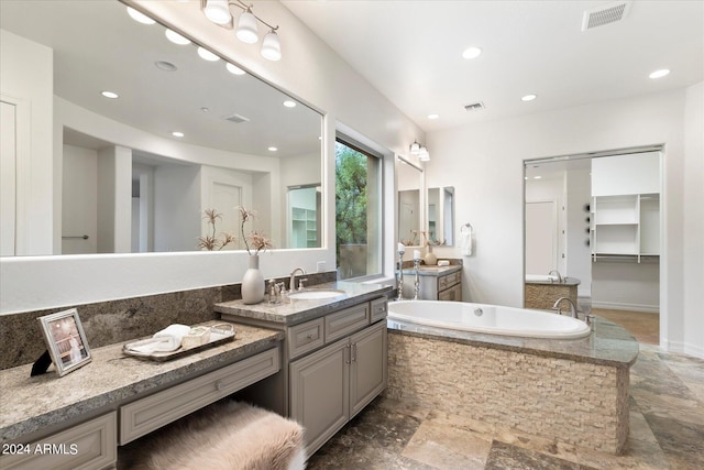 bathroom with two vanities, visible vents, a sink, and a bath