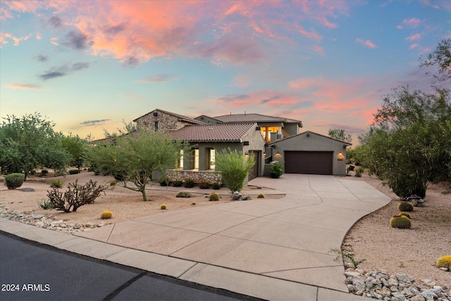 view of front of property with a garage, driveway, a tiled roof, and stucco siding