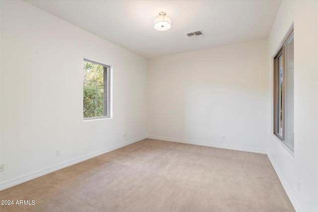 spare room with light carpet, visible vents, and baseboards