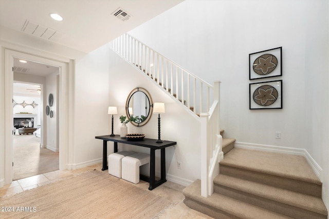 stairway featuring baseboards, visible vents, and a glass covered fireplace