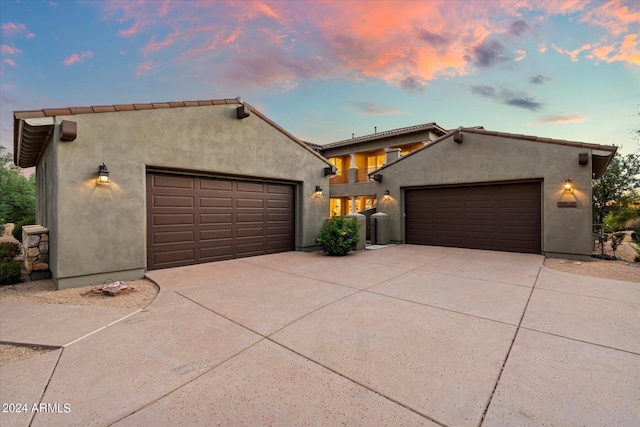 mediterranean / spanish-style home featuring a garage, driveway, and stucco siding