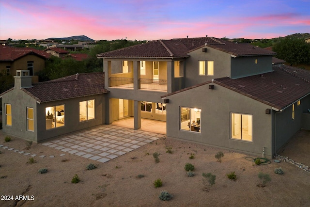 rear view of property featuring a patio, a tile roof, a balcony, and stucco siding