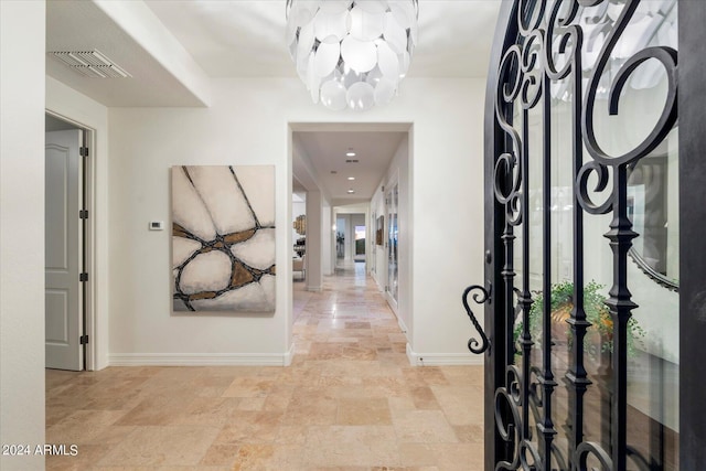 foyer with stone finish floor, baseboards, visible vents, and a notable chandelier