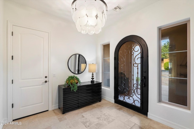 foyer entrance featuring a chandelier, visible vents, and baseboards