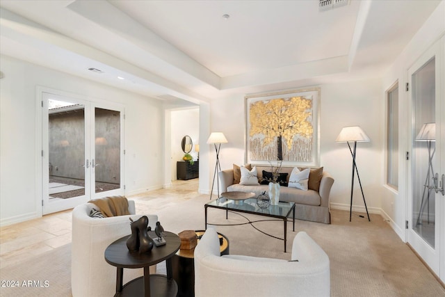 living area featuring baseboards, visible vents, a tray ceiling, and french doors