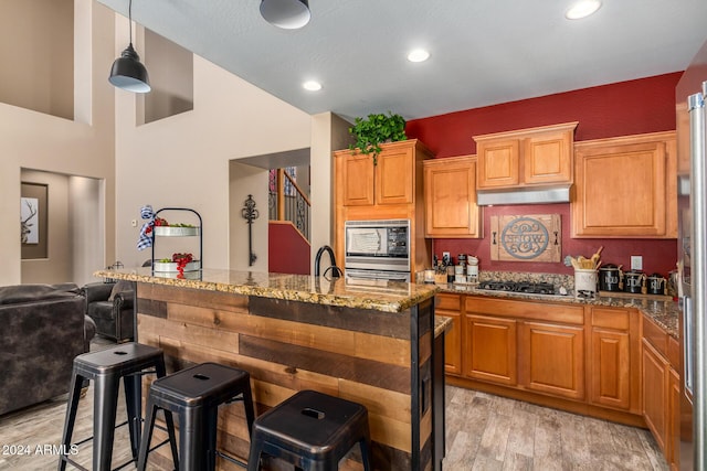 6084 W Yorktown Way, Florence, AZ 85132 - kitchen with pendant lighting, light stone countertops, a kitchen breakfast bar, light wood-type flooring, and stainless steel appliances