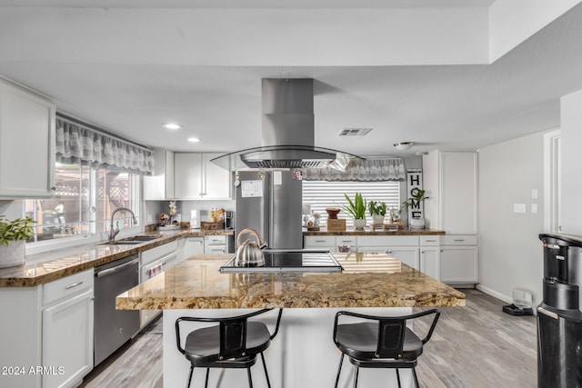 kitchen with white cabinets, island range hood, a kitchen island, and appliances with stainless steel finishes