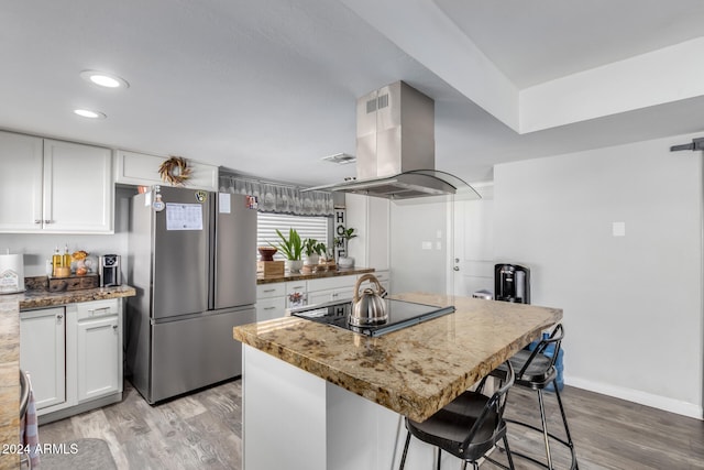 kitchen featuring island exhaust hood, stainless steel fridge, white cabinets, and light hardwood / wood-style floors