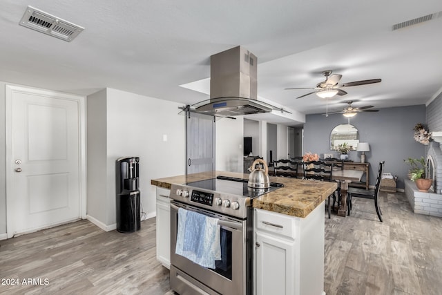 kitchen with island exhaust hood, light stone counters, electric range, light hardwood / wood-style floors, and white cabinetry