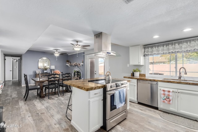 kitchen with white cabinets, sink, light hardwood / wood-style flooring, appliances with stainless steel finishes, and island exhaust hood