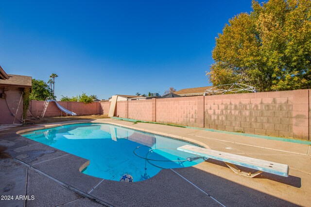 view of pool with a diving board and a water slide