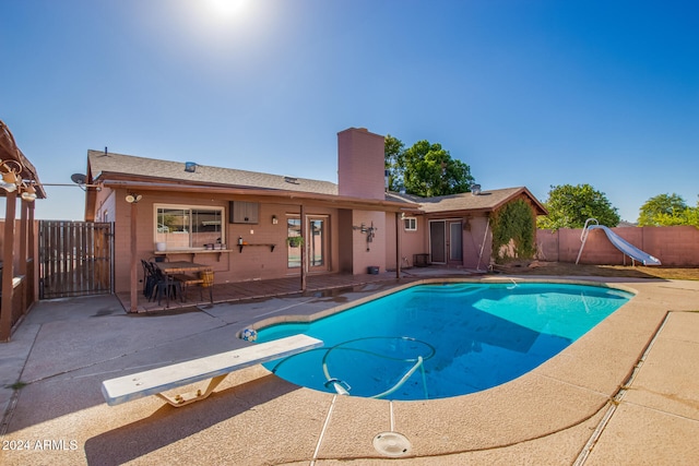 view of pool with a diving board, a patio, and a water slide