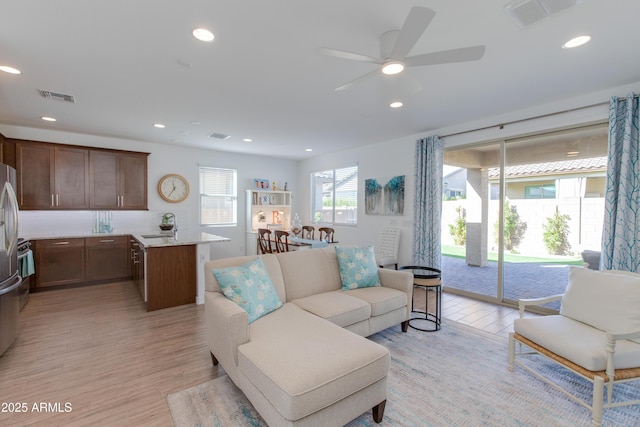 living room featuring ceiling fan, sink, and light hardwood / wood-style flooring