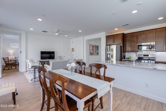 dining space featuring ceiling fan, light wood-type flooring, and sink