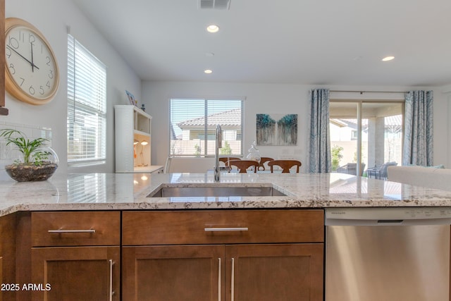 kitchen featuring light stone counters, sink, and stainless steel dishwasher