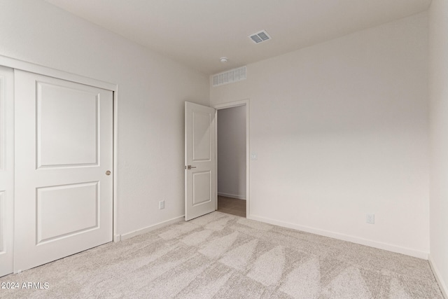 unfurnished bedroom with a closet and light colored carpet