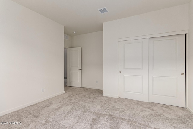 unfurnished bedroom with a closet and light colored carpet