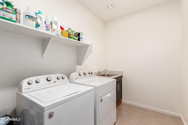 washroom with washer and clothes dryer, sink, light tile patterned floors, and cabinets