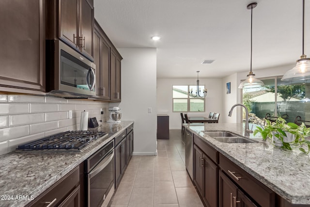 kitchen featuring decorative backsplash, decorative light fixtures, sink, stainless steel appliances, and light stone countertops