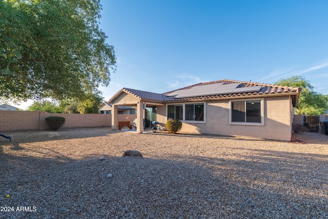 back of property with a patio and solar panels