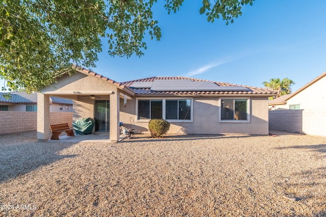 rear view of property with solar panels and a patio area