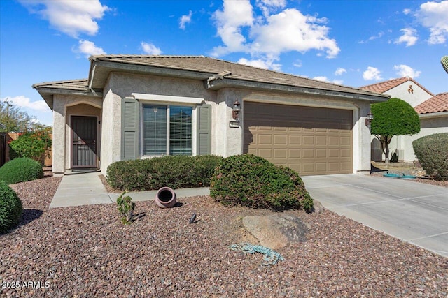 view of front facade with concrete driveway, a tile roof, an attached garage, and stucco siding