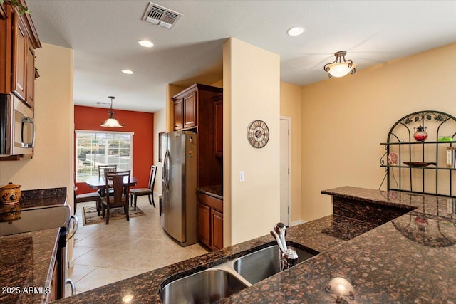 kitchen with visible vents, hanging light fixtures, appliances with stainless steel finishes, a sink, and dark stone countertops