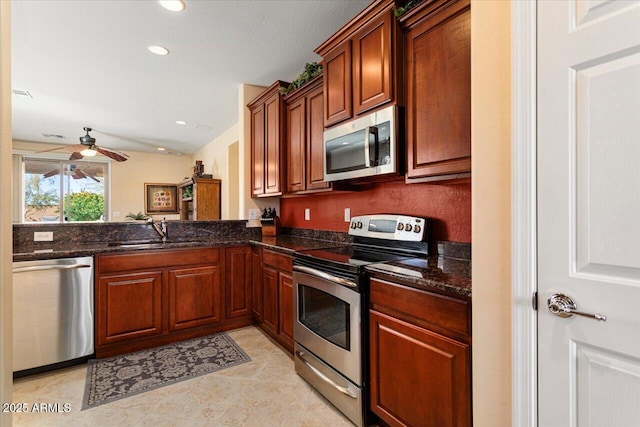 kitchen featuring dark stone countertops, stainless steel appliances, a sink, and recessed lighting