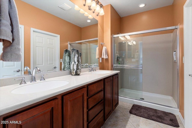 bathroom with tile patterned flooring, a sink, a shower stall, and double vanity