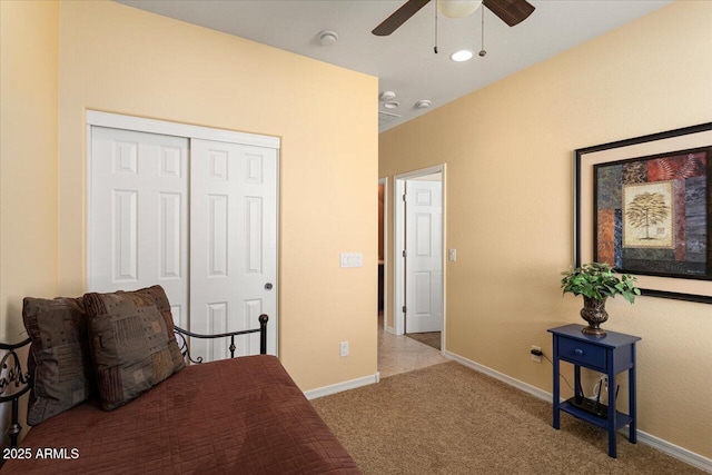 bedroom featuring light carpet, ceiling fan, a closet, and baseboards