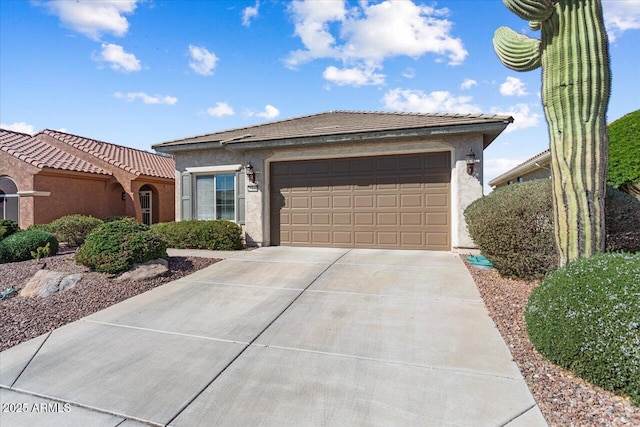 view of front of house featuring a garage, a tile roof, concrete driveway, and stucco siding