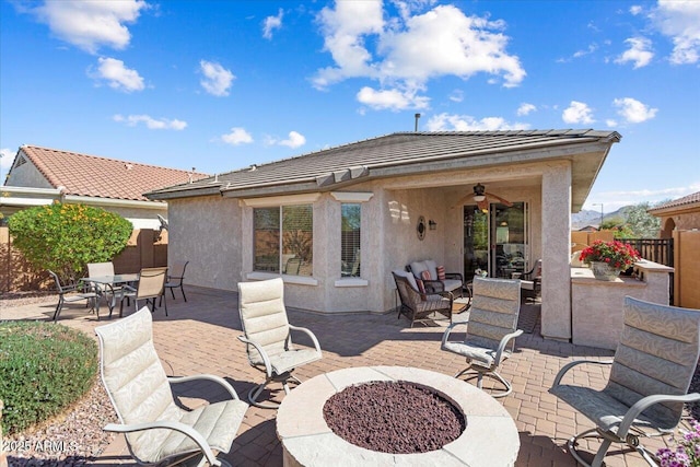 view of patio with fence, a fire pit, and a ceiling fan