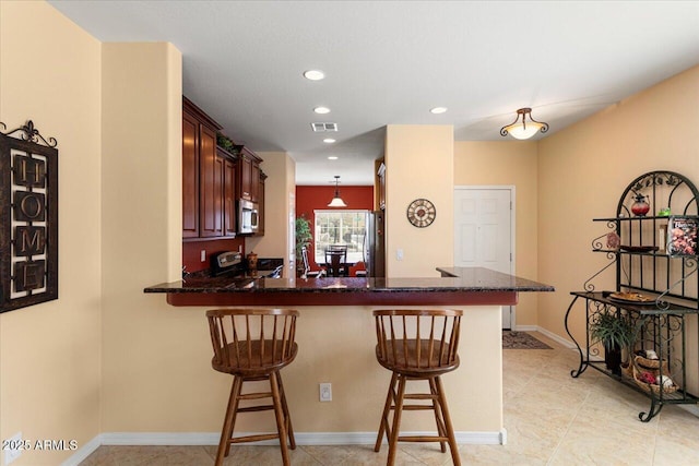 kitchen with recessed lighting, a peninsula, visible vents, appliances with stainless steel finishes, and a kitchen bar