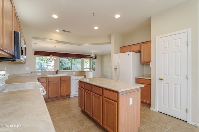 kitchen with white appliances, pendant lighting, a center island, sink, and a chandelier