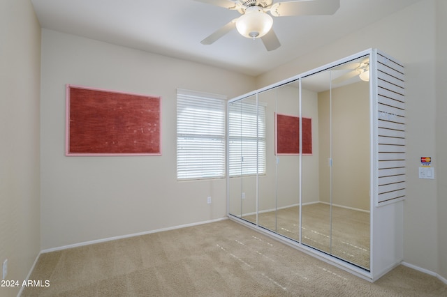 unfurnished bedroom with light carpet, a closet, and ceiling fan