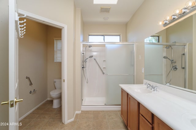 bathroom featuring tile patterned floors, a shower with door, vanity, and toilet