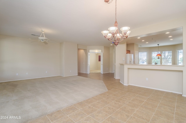 carpeted spare room featuring ceiling fan with notable chandelier