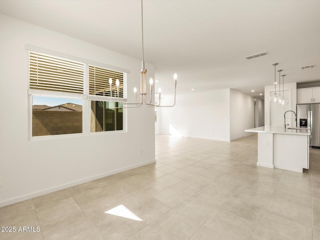 unfurnished dining area with an inviting chandelier, light tile patterned floors, and sink