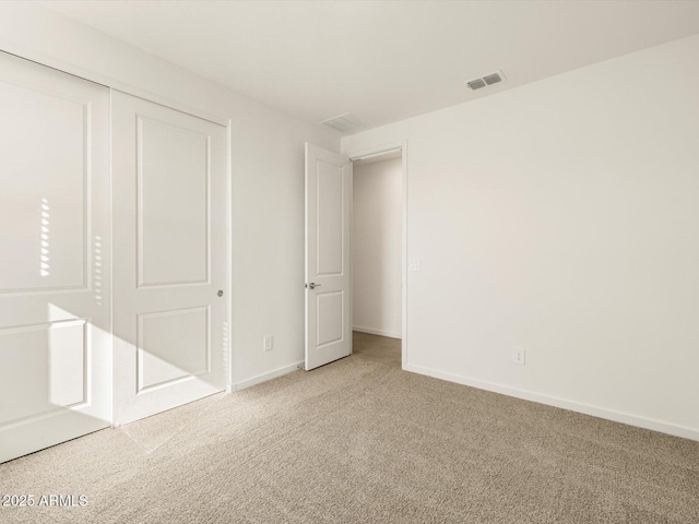 unfurnished bedroom featuring light carpet and a closet