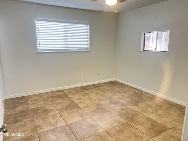 empty room with ceiling fan and light tile patterned floors