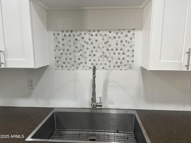 room details with tasteful backsplash, sink, dark stone countertops, and white cabinets